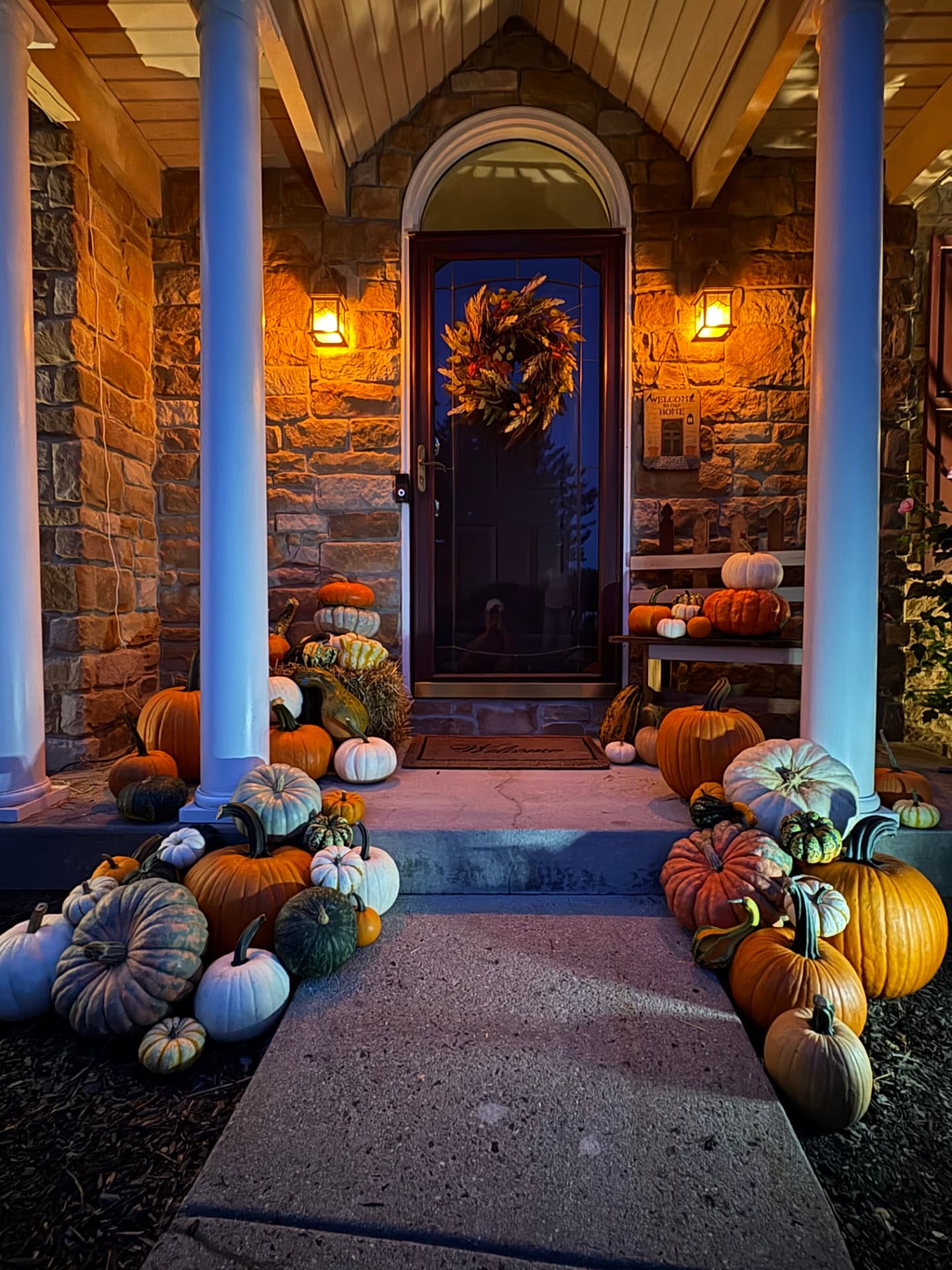 Evening view of a Premium pumpkin display lit by porch lanterns