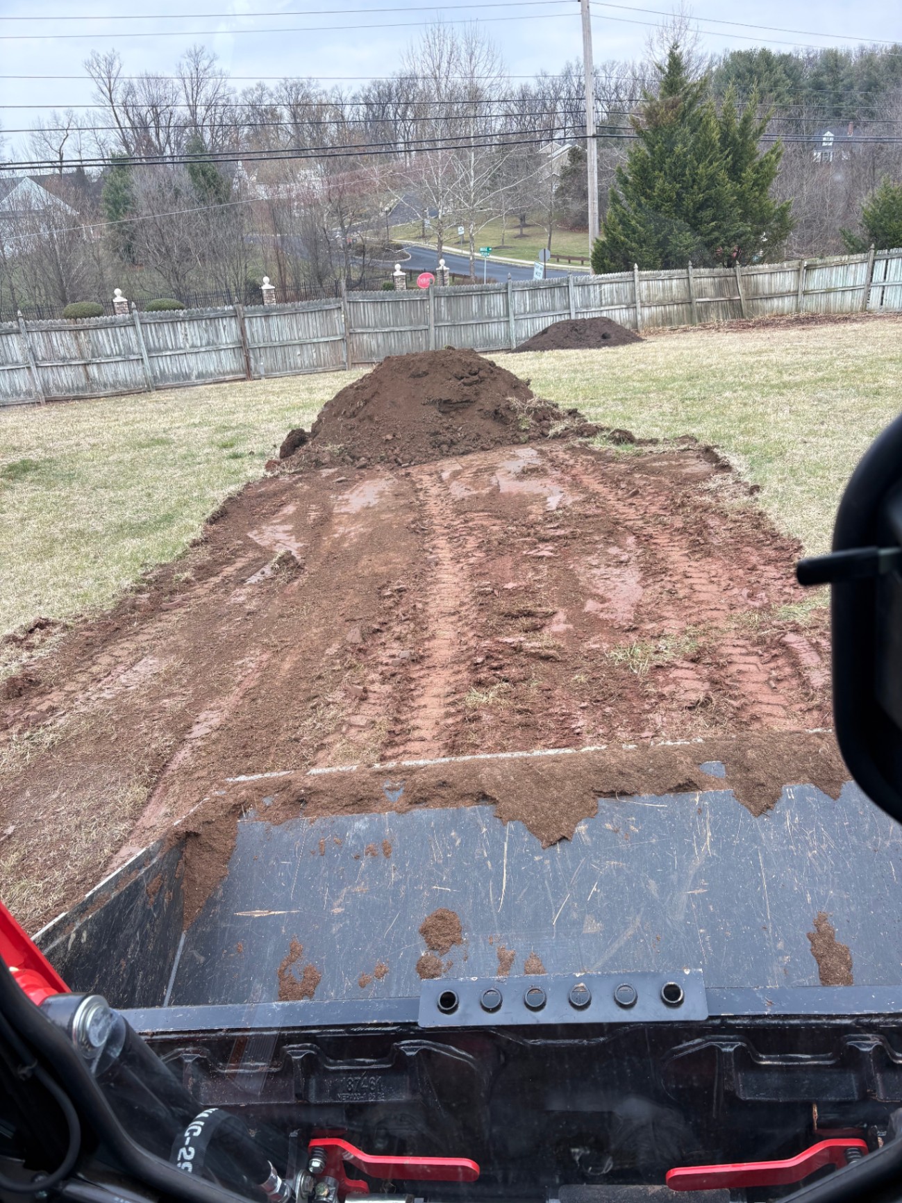 Skid steer spreading topsoil and grading a residential backyard
