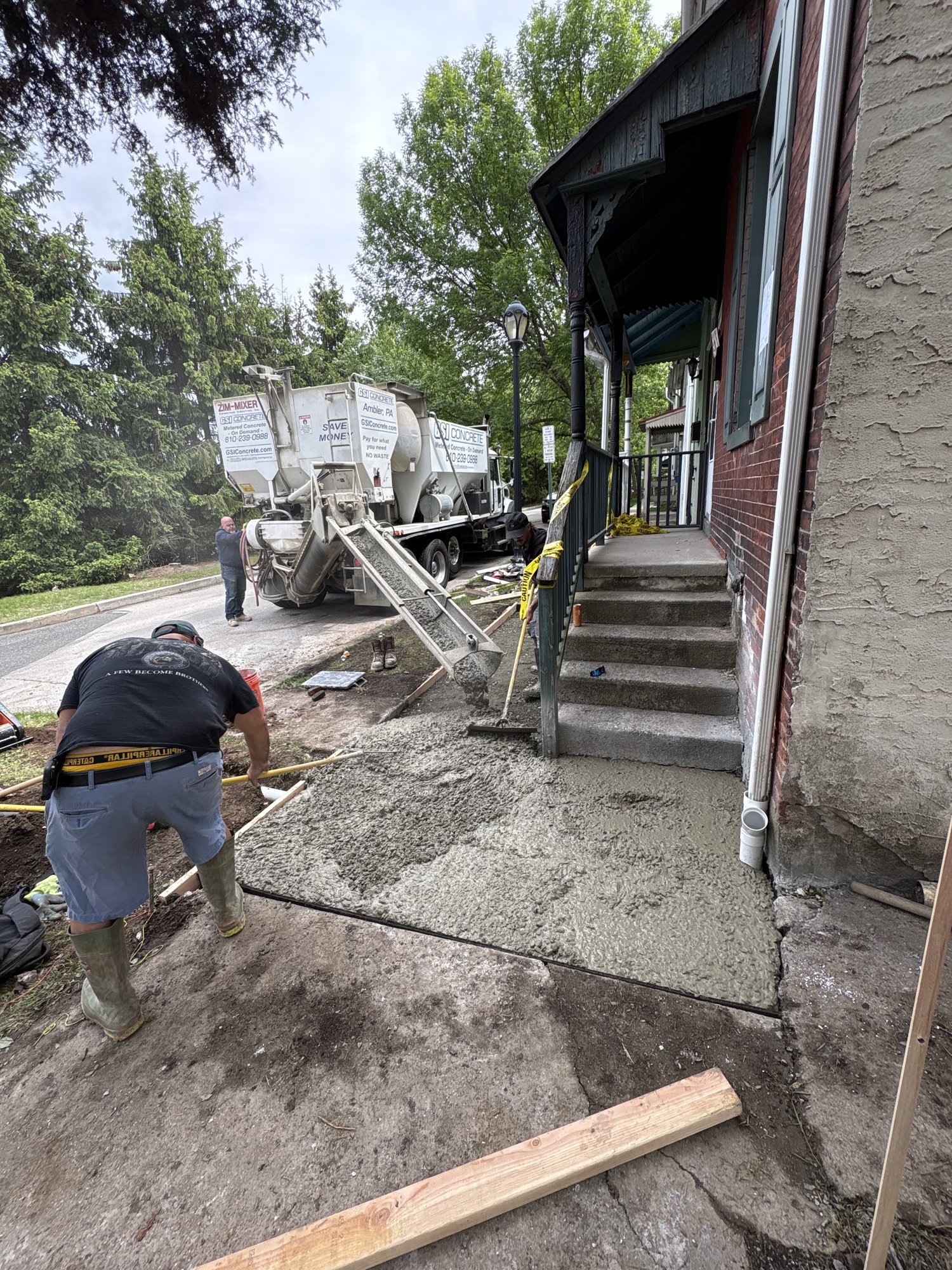 Larson Landscape crew pouring a fresh concrete walkway alongside a home with a concrete mixer truck on the street