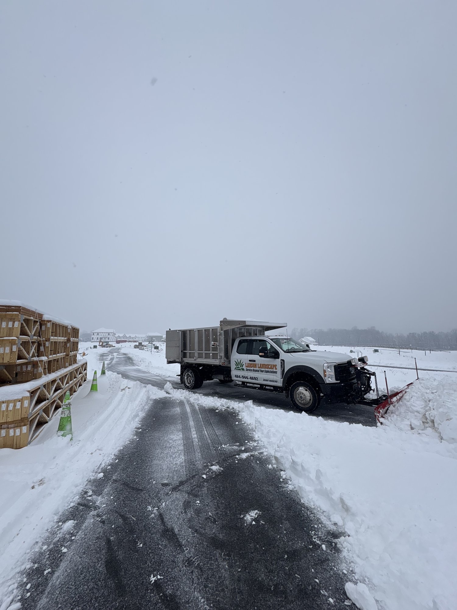 Larson Landscape plow truck cleared a commercial site road with material stacked to the side