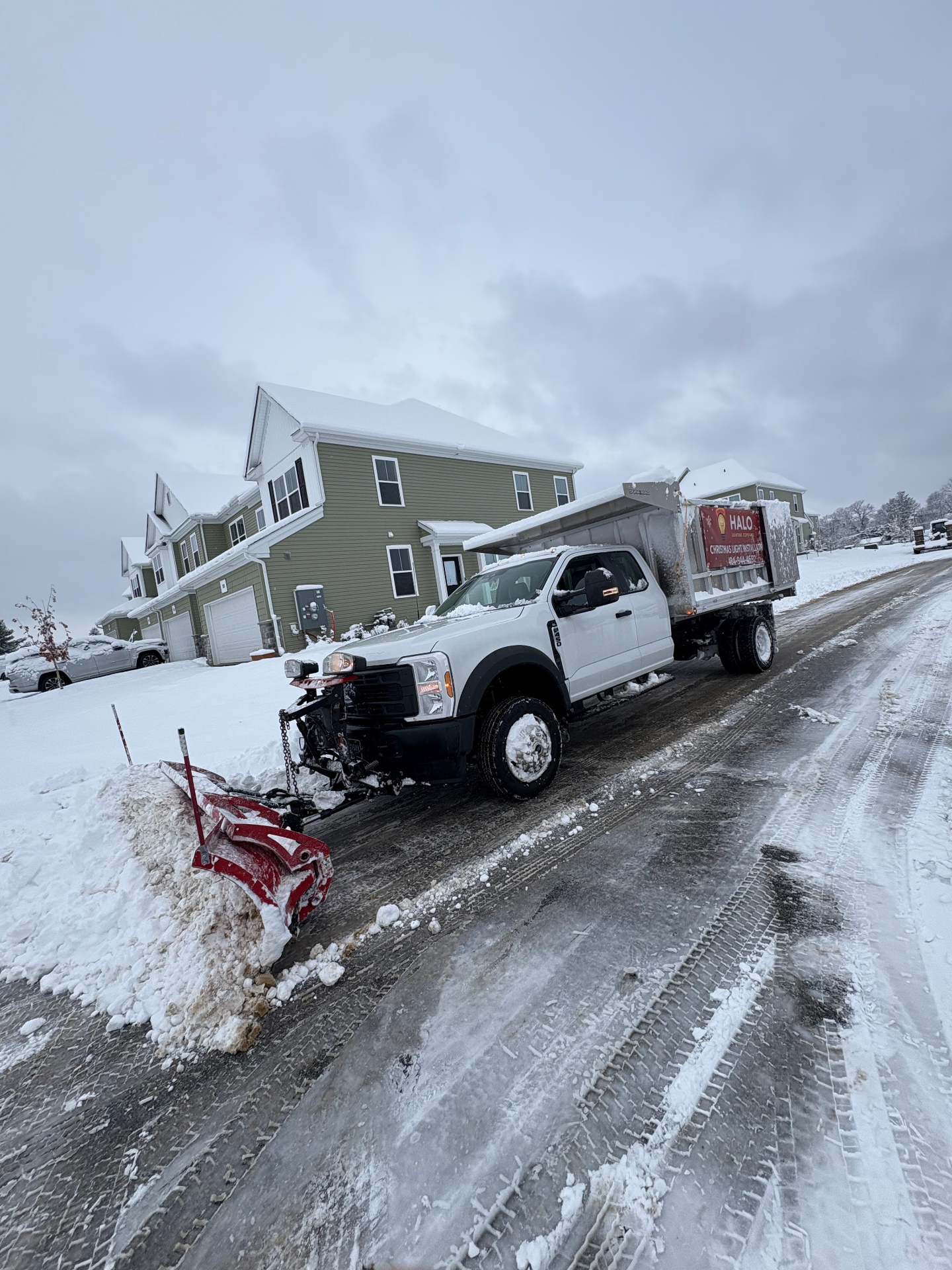 Larson Landscape plow truck clearing an HOA road with fresh snow banked on the shoulder