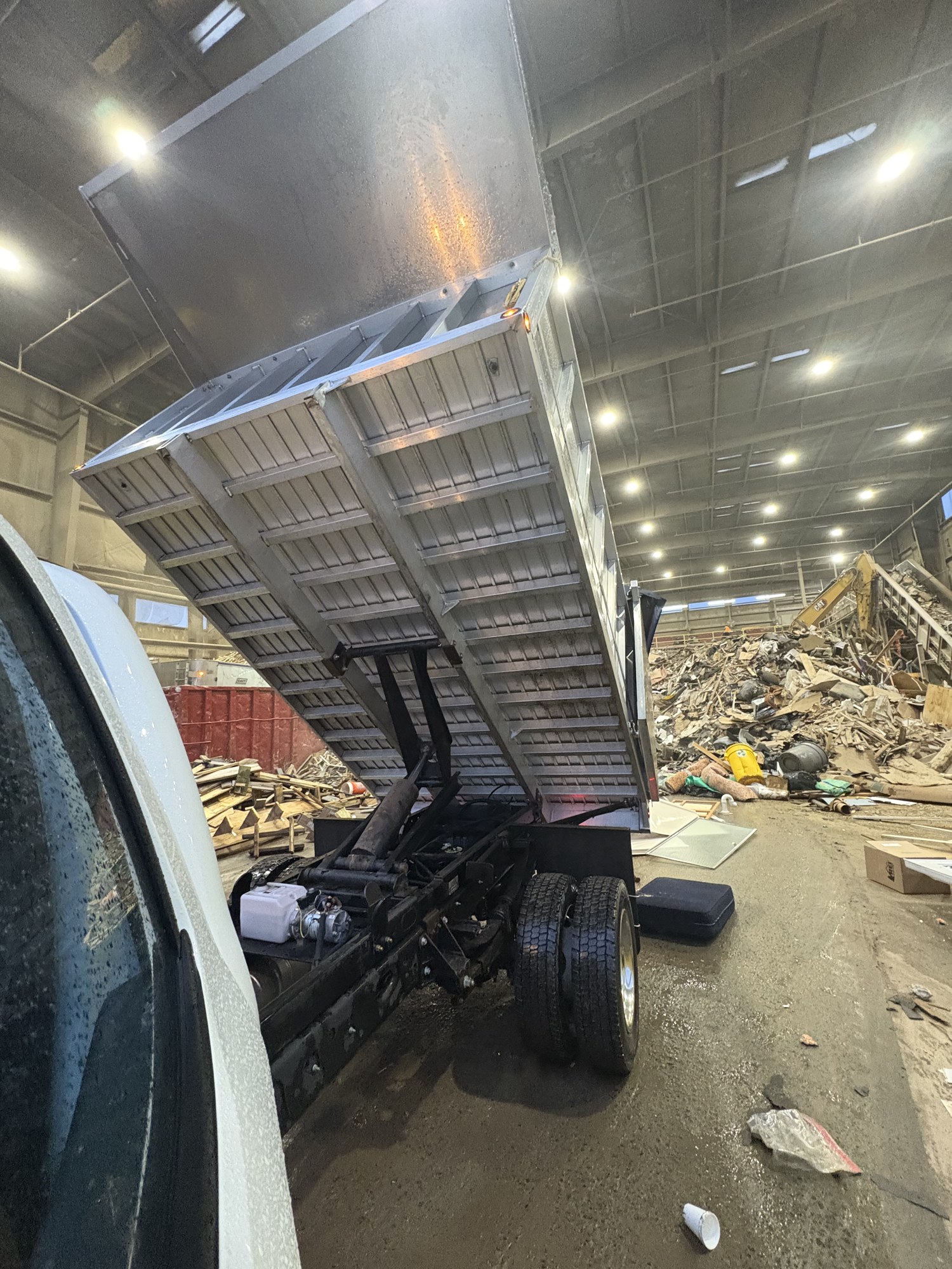 Aluminum dump bed raised inside a debris transfer station after a full junk removal drop-off