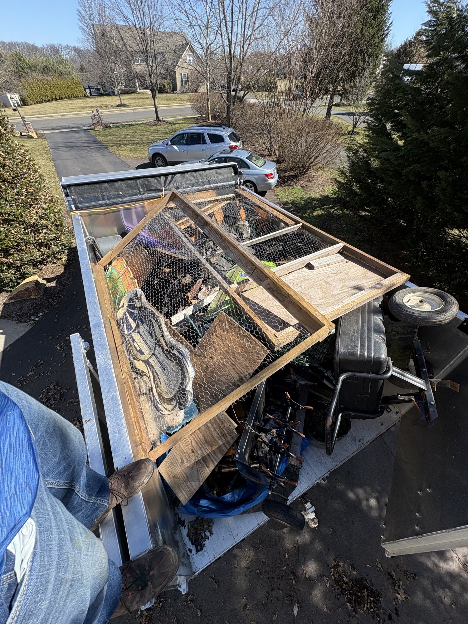 Loaded dump truck full of shed cleanout debris — old wood, chicken wire, and yard equipment