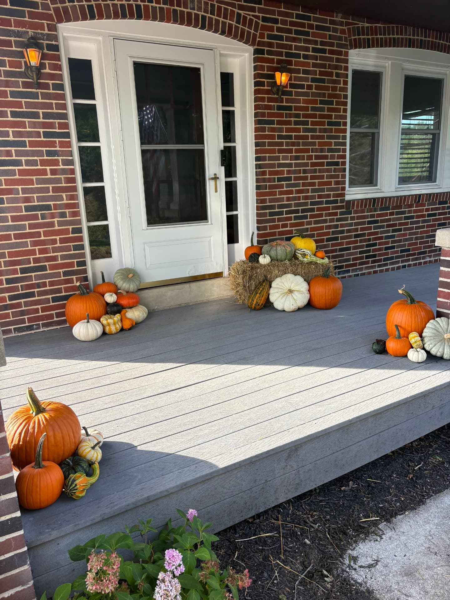 Classic Porch Pumpkins display with pumpkins and a hay bale on a covered brick porch